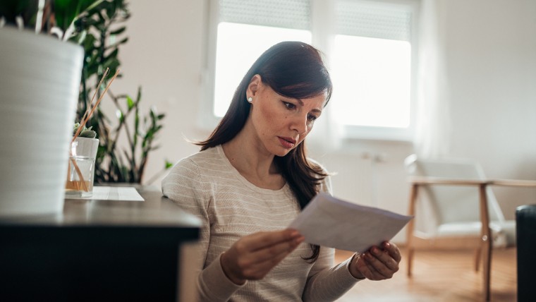 Woman looks concerned while reading letter.